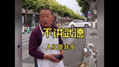 图片中显示一位穿着紫色上衣和白色围裙的男子站在城市街道旁，手持黑色物品，背景有树木、车辆和建筑物。图片中央有黄色大字叠加："不讲武德"和"人红是非多"，右下角有"木鱼游戏 (解说)"的小字标注。