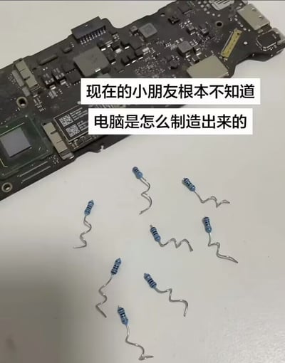 图片展示了一块电脑主板，上面有各种电子元件和芯片。主板前方摆放着几个被弯成小人形状的蓝色电阻，看起来像一群小人在面对巨大的主板。图片上方配有文字：'现在的小朋友根本不知道电脑是怎么制造出来的'，幽默地暗示现代年轻人不了解电脑硬件的制造过程，用拟人化的电阻小人形象增加了趣味性。