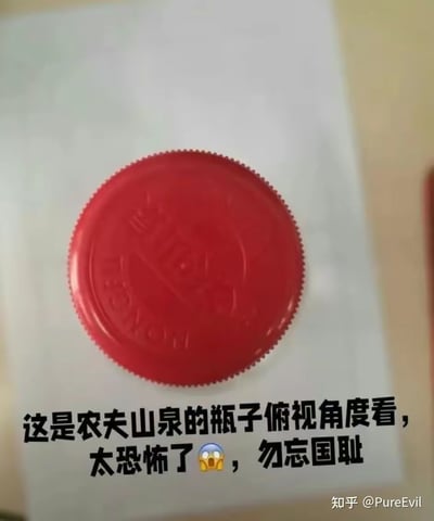 这是一张俯视角度拍摄的农夫山泉红色瓶盖照片，瓶盖的纹路在该视角下形成了容易引发联想的图案。图下方配有文字：“这是农夫山泉的瓶子俯视角度看，太恐怖了😱，勿忘国耻”，利用视觉错位制造出误解，试图引导特定联想，属于网络上流传的视觉误导类内容。