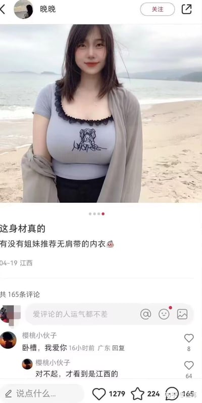 社交媒体截图展示一位女性站在海滩上，穿着灰色带卡通图案的上衣和黑色短裙，外搭灰色披肩。她的头发被风吹起，面带微笑看向镜头。配文称"这身材真的 有没有姐妹推荐无肩带的内衣"，下方显示有165条评论，其中一条评论说"卧槽，我爱你"后又道歉称"对不起，才看到是江西的"。