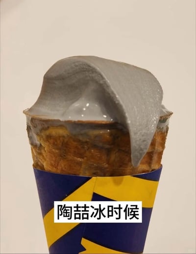 这是一张充满趣味的静态图片，主体是一支装在华夫甜筒里的灰色冰淇淋，冰淇淋部分融化并向下流淌，甜筒外包裹着蓝黄相间的包装套。图片下方配有文字“陶喆冰时候”，这是一个利用歌手陶喆名字的谐音梗，谐音“到结冰时候”，结合灰色冰淇淋类似结冰的视觉外观，将普通的美食图片赋予了网络玩梗的趣味属性，制造出轻松搞笑的效果，属于网友自发创作的创意梗图。