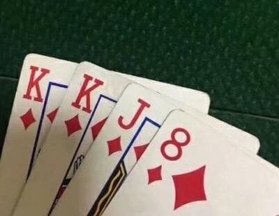 这张图展示了四张方块花色的扑克牌，依次为两张方块K、一张方块J和一张方块8，被摆放在绿色的桌布上。这组牌的字母与数字组合起来谐音中文的“哭哭唧唧”，是利用扑克牌字符玩的谐音梗，可用来表达委屈、难过、娇嗔哭泣的情绪。