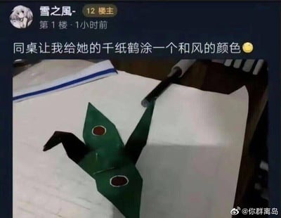 一张社交媒体截图，展示了一个涂成绿色并带有红色圆点的千纸鹤。发帖用户称同桌让其给千纸鹤涂和风颜色，结果涂成了类似日本传说中河童的形象，形成幽默效果。