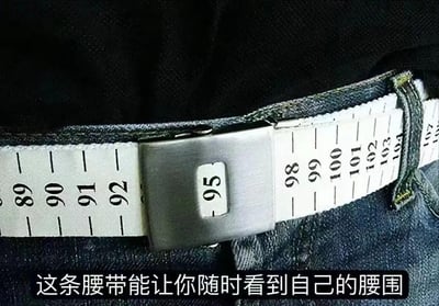 图片近距离展示了一条黑色腰带，其表面设计类似卷尺，带有从89到105的白色刻度标识。金属扣中间有一个方形窗口，清晰显示数字“95”。腰带下方配有文字说明“这条腰带能让你随时看到自己的腰围”，突出其可实时查看腰围尺寸的功能。整体画面聚焦于腰带的测量刻度和卡扣细节，背景为深色布料，使白色刻度和金属扣更加显眼。