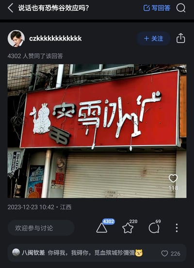 这是知乎平台上针对问题“说话也有恐怖谷效应吗？”的一则回答，由用户czkkkkkkkkkkk发布于2023年12月23日江西，获得4302人赞同。回答的核心配图是一家已关停的蜜雪冰城店铺：红色招牌上的白色金属字大面积破损脱落，原本清晰的“蜜雪冰城”字样扭曲变形，看起来像是充满诡异感的异体文字，恰好对应了“说话的恐怖谷效应”——当熟悉的信息（日常文字）变得接近原本形态但又完全陌生时，会让观看者产生不适、诡异的心理感受。回答下方的热门评论将破损的文字解读为“你碍我，我碍你，觅血殡城殄弭彌😼”，进一步放大了这种诡异恐怖的氛围，而卷帘门上的“合同到期 关停”字样也交代了店铺的状态，让这个破损招牌的场景更显萧条。