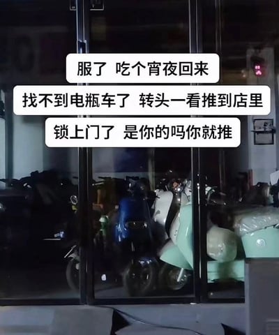 图片展示了一家店铺的玻璃门内部，可以看到几辆电瓶车停放在店内。图片上方有文字描述了一个令人无奈的生活场景：当事人吃宵夜回来发现自己的电瓶车不见了，转头才发现被人推进了这家店里，并且店门已经被锁上。文字中充满了对这种行为的不解和轻微愤怒："是你的吗你就推"。这张图片很可能是当事人遇到这种情况后拍摄并分享到社交媒体的真实生活记录。