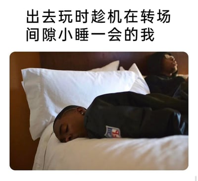 这是一张图文结合的搞笑梗图，上方配有中文文字“出去玩时趁机在转场间隙小睡一会的我”。图中展示了酒店房间内的场景：前景处一位穿着带有NFL标志黑色上衣的黑人男性侧趴在柔软的白色床品上，双眼紧闭，正熟睡，神态放松；背景处还有一位戴着眼镜的黑人男性靠在床头，与前景熟睡的人形成对比。这张图生动地还原了很多人在外出游玩时，行程紧凑导致疲惫不堪，只能抓住转场的短暂间隙补觉的真实状态，用夸张又贴合的画面引发共鸣。