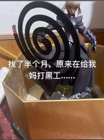 这张图是一张带字的二次元恶搞梗图，图中是《Fate》系列中人氣角色Saber的黑Saber手办，持着螺旋状武器。实际近看发现，这个“武器”其实是点燃后的蚊香，Saber手办被安置在蚊香盒内。配文“找了半个月，原来在给我妈打黑工……”带有幽默自嘲，表达手办变成家用物品，被妈妈拿去点蚊香的搞笑场景。该图利用了现实道具和二次元手办场景的错位，形成反差与幽默感。没有明显双关和谐音梗，但存在家庭日常与ACG文化的反差暗示。
