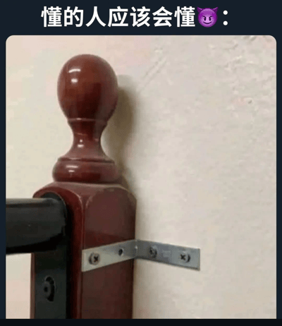 图片展示了一个室内场景，特写拍摄了一个木质扶手的顶部。扶手顶部是一个圆形的木球，下方连接着方形的木柱，通过金属支架固定在浅色的墙壁上。图片上方有文字"懂的人应该会懂😈"，暗示扶手的形状可能存在某种双关或暗示意义。