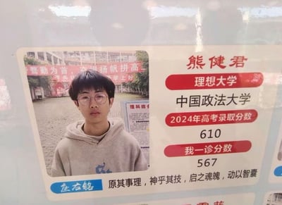 这是一张用于高考备考激励的个人目标展示卡，内容包含：<br>1. 学生熊健君的个人照片，他穿着灰色连帽卫衣，背景是带有“整勤为首，扬帆拼高”励志标语的校园场景；<br>2. 目标院校为中国政法大学，该校2024年高考录取分数为610分，该生一诊分数为567分，体现出分数提升的空间；<br>3. 个人座右铭为“原其事理，神乎其技，启之魂魄，动以智囊”，传递出沉稳励志的备考态度。图片无谐音梗、双关或暗示类内容。