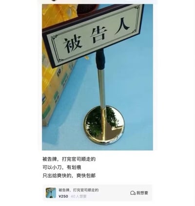 图片展示了一个法庭上使用的被告牌，配有文字说明这是"打完官司顺走的"，并以250元价格出售，带有"可以小刀，有划痕"等典型二手交易用语，下方还有类似电商平台的商品展示界面。通过将严肃的法律物品作为普通二手商品出售的反差，制造幽默效果。
