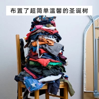这是一张充满生活趣味的搞笑实拍图，画面中一把木质靠背椅上被堆满了色彩各异的待整理衣物，这些衣物被堆叠成了类似圣诞树的锥形外观。图片顶部配有文字“布置了超简单温馨的圣诞树”，用自嘲式的幽默，将生活中懒得整理的堆积衣物，包装成了“圣诞布置”，用轻松搞笑的方式调侃自己的拖延，旁边的熨衣板也暗示了这些衣物是待熨烫整理的，整体氛围轻松诙谐，充满生活烟火气的趣味。