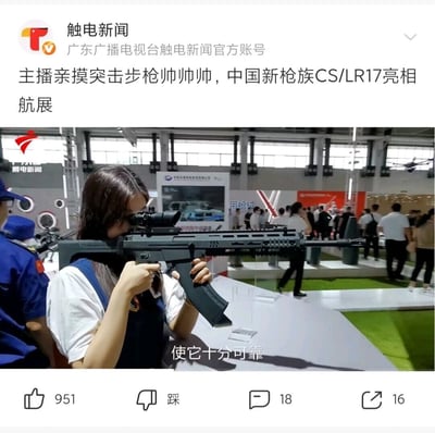 这是广东广播电视台触电新闻发布的航展现场报道内容，画面核心是一位女新闻主播正在体验中国新枪族CS/LR17突击步枪，她双手持枪，将眼部贴近枪械的瞄准镜进行瞄准动作。这款步枪外观现代化，配备了瞄准镜，枪身有模块化的护木设计。背景是航展的室内展会现场，能看到不少参观的人群在展位间走动，还有其他展商的展位和展示内容，画面下方的字幕标注“使它十分可靠”，用于介绍这款枪械的可靠性能。整体场景热闹，直观展示了这款新型军事装备的细节，通过主播体验的方式让观众更有代入感。