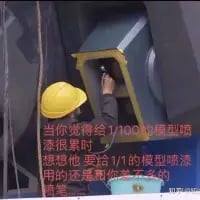 这是一张模型圈的趣味梗图，画面为真实拍摄的场景：一个人只能从狭小的窗口中伸出手。图中配文玩模型制作的梗：当你觉得给1/100比例的模型喷漆已经很累的时候，想想这个要给1/1比例（真实大小）的“模型”喷漆的人，他的工作量还是你的两倍，用夸张的对比来调侃模型喷漆的辛苦，消解爱好者的疲惫感。