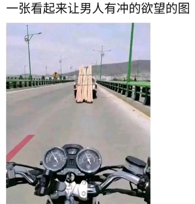 图片上方配有文字'一张看起来让男人有冲的欲望的图'，下方主体为摩托车第一视角拍摄的公路场景：前方道路上有一辆卡车装载着多根木板，道路两侧有路灯和护栏，远处可见山丘和城市轮廓。图片通过标题的暗示性文字与实际摩托车视角下的公路场景形成幽默反差，'冲的欲望'在这里双关指驾驶摩托车想要超越前方车辆的冲动。