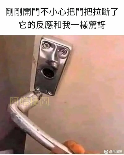 这是一张充满趣味的日常实拍梗图，图中用户在开门时意外拉断了金属门把手，而门上残留的锁座部分，因两颗螺丝的位置对应眼睛、锁孔对应嘴巴，巧合形成了一张露出惊讶表情的人脸形态。配上文案“刚刚开门不小心把门把拉断了，它的反应和我一样惊讶”，将无生命的锁座拟人化，生动地表现出当事人拉断门把手时的意外感，也让场景充满了幽默的反差效果，引发观者的共鸣与笑意。