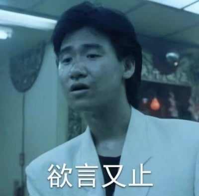 图片中是香港演员曾志伟，他穿着白色西装，表情犹豫，眼神中带着一丝复杂的情绪，似乎有话想说却又停住了。图片下方配有文字“欲言又止”，精准地概括了他此刻的状态。这张截图常被用作表情包，用来表达人们在某些场合下想说但又不方便说，或者犹豫不决的心情。