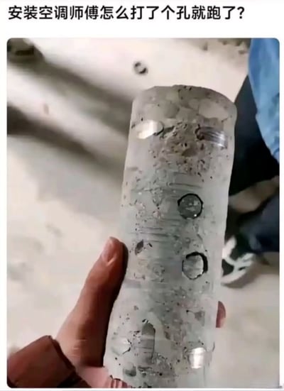 图片中一只手握着一个圆柱形的混凝土柱芯，柱芯表面粗糙，带有多个大小不一的圆形钻孔痕迹。图片上方配有文字“安装空调师傅怎么打了个孔就跑了？”，暗示空调安装师傅在钻孔后异常离开，引发观者对柱芯上多钻孔原因的好奇与疑惑，整体场景带有生活中的搞笑与不解氛围。