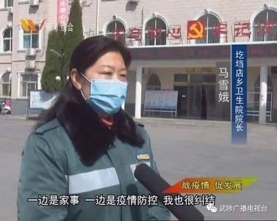 这是一张新闻采访的视频截图，画面主体是圪垱店乡卫生院院长马雪娥，她身着带有毛领的深绿色工作服，佩戴蓝色医用口罩，正面对采访话筒讲话。背景是卫生院的办公建筑，建筑上方有“不忘初心 牢记使命”的字样与党徽标志。画面右侧竖排标注了采访对象的身份“圪垱店乡卫生院院长 马雪娥”，画面下方配有字幕“一边是家事 一边是疫情防控 我也很纠结”，还有“战疫情 促发展”的宣传标语，左上角有“新闻综合”的台标，右下角则有“武陟广播电视台”的水印，整体展现了疫情期间基层医疗工作者在家庭责任与防疫工作之间的两难处境。