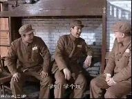 图片中三位身着军装的男性并排坐在长椅上，背景为砖墙结构，整体场景呈现出严肃的氛围。画面底部有白色字幕文字“中出了个叛徒”，暗示场景中存在背叛者的情节设定。