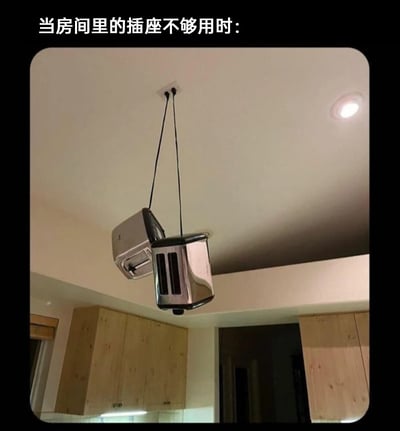 这是一张带有文字加注的厨房场景静态图，图片顶部配文“当房间里的插座不够用时：”，画面中天花板的插座上插着两个烤面包机，并用绳子将它们悬挂在空中，以此来“解决”插座不足的问题。这种操作完全违背了电器的正常使用场景和安全规范，以荒诞、脑洞大开的方式制造出搞笑效果，用来调侃生活中插座不够用的窘境。