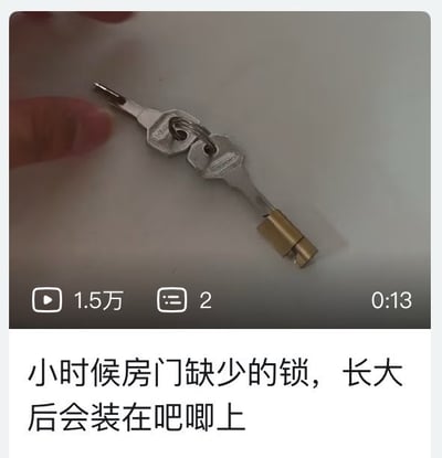 这是一张图文混排的视频截图，上方为时长13秒的短视频截帧：画面中同一个钥匙环串着两把金属钥匙，其中一把钥匙的末端套接了一个迷你黄铜挂锁，画面左上角露出部分人体手指，视频界面显示播放量1.5万、评论数2；下方配文“小时候房门缺少的锁，长大后会装在吧唧上”，对应二次元爱好者的共鸣梗：小时候渴望给自家房门装锁拥有独立私密空间，长大后收集吧唧（音译自badge，指代二次元徽章类周边）时，会给珍贵的吧唧加装保护措施甚至锁具来避免周边被损坏或触碰。