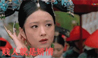 图片为电视剧《甄嬛传》中角色华妃的经典场景截图。华妃身着古装，头戴装饰有蓝色花朵的华丽旗头，侧头抬手整理发饰，眼神轻蔑，表情不屑。图片底部有醒目的红色文字‘贱人就是矫情’，这是华妃的标志性台词。该台词原用于讽刺他人装模作样，后在网络文化中演变为戏谑调侃虚伪做作行为的流行语。