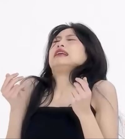这张图片中，一位长发女生穿着黑色吊带上衣，双手摆在胸前，手指微翘，似乎正在做一个夸张的表演或搞怪的动作。整体姿势显得非常戏剧化和有表现力，经常被用来表达“无语”、“崩溃”或者“啊我忍不了了”等网络情绪。图片背景为单色纯白，突出人物主体，明显是出自拍摄棚或类似场景。