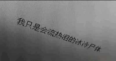 这是一张纯文字静态单图，背景为浅灰色带有细微纹理的平面，黑色文字呈倾斜样式排版，文字内容为“我只是会流热泪的冰冷尸体”。这句话运用了矛盾的表述方式，将代表无生机、麻木的“冰冷尸体”与代表有情绪、柔软的“流热泪”结合，精准传递出一种内心如同失去活力般麻木，但又依然残留着悲伤情绪的复杂心境，通常用来抒发人们在面对压力、孤独等负面境遇时的矛盾感受，既有对自身状态的无力感，又有未完全被磨灭的情绪感知。