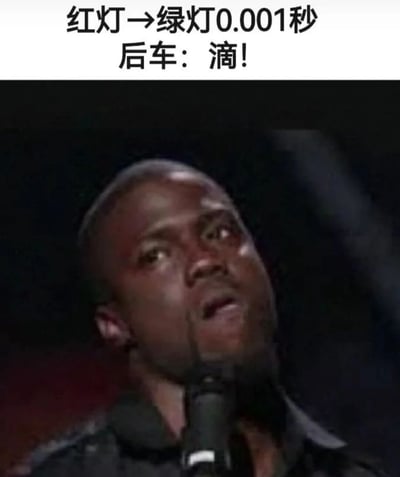 这是一张幽默梗图，上方配有文字“红灯→绿灯0.001秒 后车：滴！”，下方是一位表情惊讶的黑人男性抬头看向斜上方，嘴巴微张，手持麦克风的画面。图片通过夸张的时间描述（0.001秒）和后车立即按喇叭的反应，幽默地表现了现实生活中一些司机在交通信号灯刚变绿时就不耐烦地按喇叭催促前车的现象。