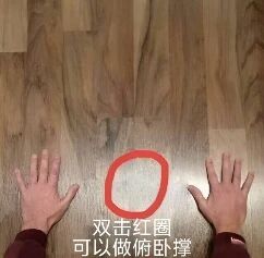 图片展示了木地板背景上，两只真人手掌分别放在左右两侧，中间用红色圆圈标记。底部配有文字“双击红圈 可以做俯卧撑”，通过将数字界面中的“双击”操作与现实中的俯卧撑运动结合，制造出幽默效果，调侃了数字交互习惯对现实行为的有趣影响。
