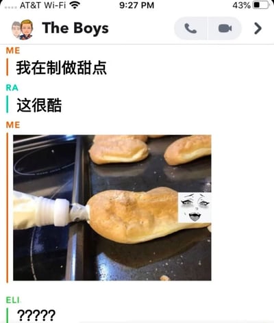 这是一张聊天记录截图，展示了一个名为"The Boys"的群组对话。对话中，"ME"表示自己在制作甜点，"RA"回应"这很酷"，随后"ME"发送了一张图片，显示正在给一个形似男性生殖器的甜点挤奶油，甜点上还被编辑添加了一个惊讶的表情包脸。最后"ELI"用"?????"表达了困惑。图片通过将甜点形状与表情包结合，制造出一种滑稽又尴尬的喜剧效果。