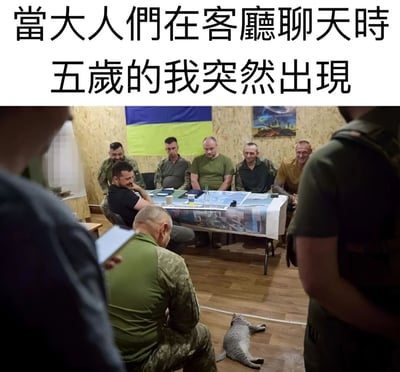 图片上方有文字'当大人们在客厅聊天时 五岁的我突然出现'，下方是一张现实场景照片，内容为一群穿着军装风格服装的男性围坐在桌子旁开会，桌上有地图等物品，地板上躺着一只猫。通过将严肃的军事会议场景与童年突然闯入大人聊天场景的文字结合，形成反差幽默，调侃童年时不懂事突然打断大人谈话的经历。