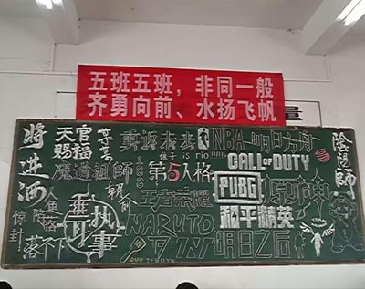 这是一间教室的实拍场景，上方悬挂着红色的班级口号横幅，写着「五班五班，非同一般，齐勇向前、水扬飞帆」。下方的绿色黑板报被学生写满了当下热门的各类流行文化内容，涵盖网文IP（《将进酒》《天官赐福》《魔道祖师》《朝俞》《人鱼陷落》等）、游戏（《第五人格》《王者荣耀》《原神》《阴阳师》《PUBG》等）、动漫（《NARUTO》）、赛事（NBA）等，右下角还手绘了《原神》中的角色派蒙，整体充满了青春学生的喜好集合，没有双关、谐音梗或暗示内容。