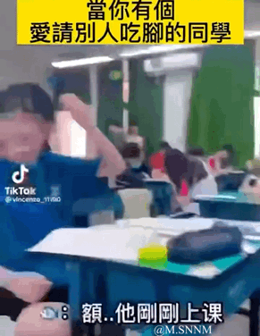 这是一组展现校园同学间搞怪互动的连环视频截图，场景发生在教室内：一开始戴口罩的男生对着镜头一本正经地澄清，随后画面切换到他凑近蓝衣服女生的脚，女生立刻大喊“你不要再！！！”；接着女生大笑着把脚往男生方向凑，男生做出躲避的动作；最后女生调侃男生“你暗恋我？”。整个过程充满了校园同学间轻松玩闹的趣味氛围，没有谐音、双关或暗示类的内容，就是单纯的日常整活。