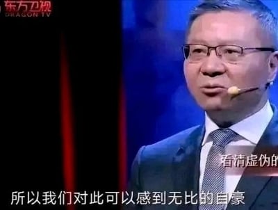 图片显示一位戴着眼镜、穿着深色西装和领带的中年男子正在舞台上讲话。背景为深色，左侧有红色幕布装饰，左上角可见东方卫视(DRAGON TV)的标志。男子佩戴着耳麦，表情严肃认真。图片底部有两行白色字幕文本：'看清虚伪的'和'所以我们对此可以感到无比的自豪'。