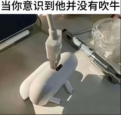 图片上方配有文字'当你意识到他并没有吹牛'，下方为办公桌场景实拍图。桌面上有一个白色的形似小型火箭或机械部件的物体，被夹具固定着，旁边放有透明玻璃杯和金属质感的笔。整体场景给人一种'原本以为是吹牛，结果真的做到了'的意外感。