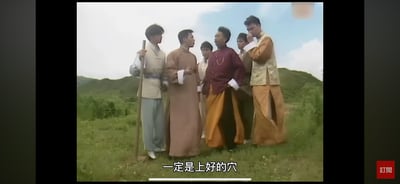 这是一张香港TVB民国题材影视剧的截图，画面中六位身着民国中式服饰的男性站在郊外绿意盎然的山坡草地上，人物姿态各异：有的手持长棍，有的叉腰，有的手放在嘴边作思考状，几位角色正围在一起交流，画面底部的简体字幕显示“一定是上好的穴”，结合场景推测是剧中角色在讨论风水吉地的相关内容，整体氛围偏向严肃的勘测讨论。