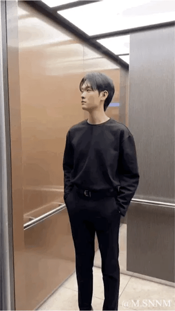 这是一段充满创意的动态内容：先是一位身着浅色长款羽绒服、围着白色围巾的女生在楼梯间抬手做出手势，随后画面切换到电梯门打开，出现一位身穿全黑服饰的男生，接着男生在电梯内做出对应手势，借助电梯门的视觉错位效果，营造出两人隔空互动的趣味场景，整体充满巧思和趣味性。
图中没有双关、谐音梗或暗示内容。