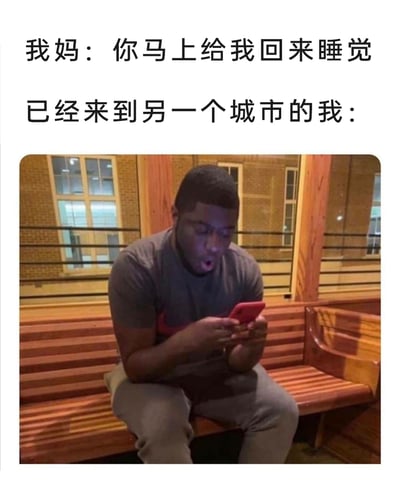 这是一张图文混排的搞笑梗图，上方分两行呈现文字内容：第一行是妈妈的指令“你马上给我回来睡觉”，第二行标注“已经来到另一个城市的我：”，下方搭配一张黑人男子的照片。照片里的男子坐在木质长椅上，双手捧着红色手机，瞪大双眼、嘴巴张开，满脸惊讶又慌张，生动表现出已经跑到另一城市的人，突然被妈妈要求回家时的震惊、不知所措的状态，通过现实处境与家长要求的反差，以及夸张的表情制造出搞笑效果，贴近年轻人脱离家长管控后被“查岗”的真实心理。
