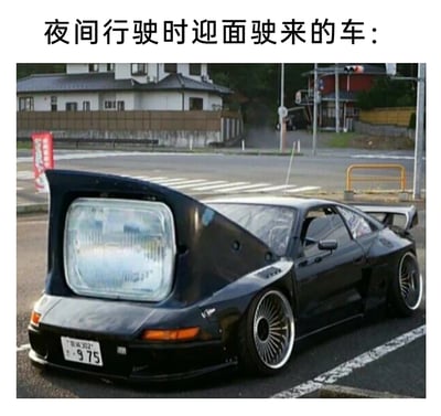这是一张用于吐槽夜间行车远光灯的搞笑P图，图片顶部配有文字“夜间行驶时迎面驶来的车：”，主体是一辆经过夸张改装的黑色低趴跑车，车头部分被替换成了一个尺寸巨大的汽车前大灯，用这种荒诞且极具视觉冲击力的改装效果，生动地调侃了夜间开车时，被对面车辆刺眼的远光灯晃眼的体验，放大了司机面对不规范使用远光灯时的无奈感，用幽默的方式引发有相同经历的司机的共鸣。