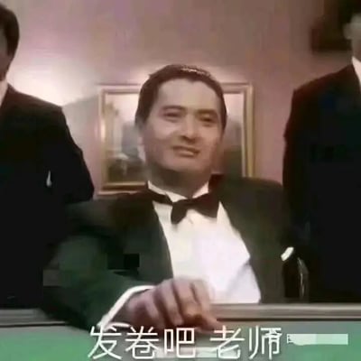 这是一张经过文字改编的影视截图表情包，画面主体是香港电影《赌神》中周润发饰演的高进，他身着黑色礼服搭配白色衬衫与领结，坐在桌前，面带自信从容的微笑，一只手搭在桌沿，还原了电影里赌神准备发牌的经典场景。图片下方添加了文字“发卷吧老师”，将赌神发牌的动作与学生等待考试发卷的场景结合，用诙谐的玩梗方式，表达学生等待考试开始时的心情，带有调侃和自嘲的意味，很适合在学生群体中用来交流考试相关的话题。