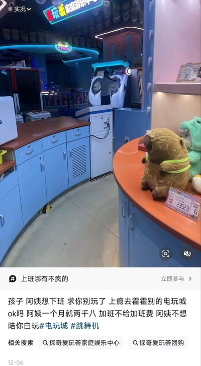 图片展示了一家电玩城内景，蓝色柜台、跳舞机等游戏设备清晰可见，柜台上摆放着棕色和绿色毛绒玩具。下方配文是电玩城工作人员的无奈吐槽：“孩子 阿姨想下班 求你别玩了 上瘾去霍霍别的电玩城 ok吗 阿姨一个月就两千八 加班不给加班费 阿姨不想陪你白玩”，道出了低薪加班的职场心酸。