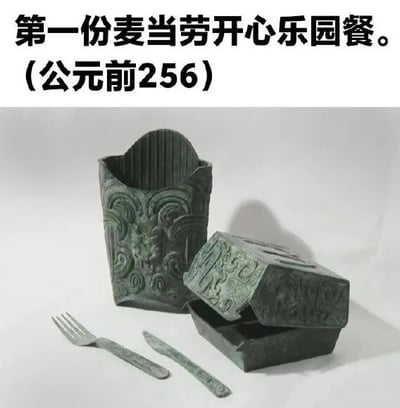 图片上方有文字“第一份麦当劳开心乐园餐。（公元前256）”，下方展示了一组形似麦当劳开心乐园餐包装（包括容器、盒子）和餐具的青铜器，器物表面有典型的古代青铜纹饰。通过将现代快餐文化符号与中国古代青铜器造型结合，制造出强烈的时空错位幽默效果，属于历史梗与品牌元素的创意混搭。