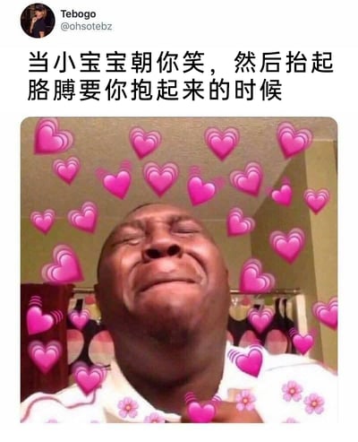 这是一张经过二次创作的表情包图片，图片上方配有中文文字“当小宝宝朝你笑，然后抬起胳膊要你抱起来的时候”，主体是一位黑人男性，他双眼紧闭、面部皱起，呈现出被深深感动到近乎哭泣的神情，画面中布满了带有动态效果的粉色爱心，人物的衣服上还添加了小花图案装饰，生动地诠释了人们在被小宝宝依赖、主动亲近时，内心瞬间涌起的强烈暖心与感动情绪，这种情绪激动到难以自持的状态，精准戳中了人们在与软萌小宝宝互动时的柔软内心，引发共鸣。