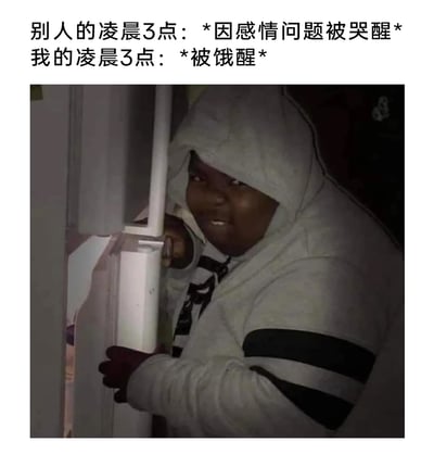 这是一张充满生活反差感的搞笑梗图，通过文字对比了两种截然不同的凌晨3点状态：他人在深夜因感情问题情绪崩溃被哭醒，而自己则是被饥饿感叫醒，偷偷开启觅食模式。图片中的黑人男子穿着灰色连帽衫，在昏暗的环境里小心翼翼地扶着冰箱门，脸上带着窃喜又紧张的表情，生动还原了深夜饿醒后不敢声张、悄悄找吃的的真实模样，用幽默接地气的内容展现了当代年轻人不同的深夜日常，极易引发网友共鸣。
