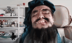 这是一段搞笑的真人动态图，图中男子将一块蓝色布料套在头上，做出一系列搞怪动作：先是布料完全盖住脸部，随后慢慢露出夸张滑稽的脸，还双手扯着布料，表情扭曲搞怪，整个过程充满了滑稽的氛围，非常适合用作搞笑表情包来传递搞怪的情绪。