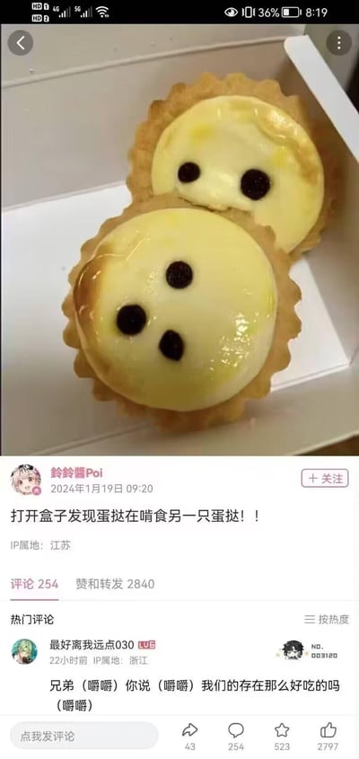 这是一张微博平台的实拍分享截图，博主打开蛋挞盒时，发现两个表面点缀黑加仑的蛋挞因摆放位置形成趣味视觉错位：上方蛋挞的两颗黑加仑像眼睛，下方蛋挞的三颗黑加仑则像被咬出的洞，看起来仿佛是上方蛋挞在“啃食”下方蛋挞。博主配文「打开盒子发现蛋挞在啃食另一只蛋挞！！」，热门评论也顺势玩梗，模仿被“啃”的蛋挞口吻吐槽，整体氛围轻松搞笑，利用巧合的视觉错位制造出荒诞有趣的效果。
