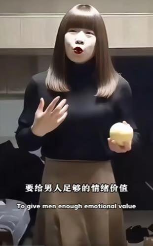 这是一张基于南京红姐网络梗改编的搞笑静态图，画面中的齐肩棕发女性身着黑色高领上衣搭配卡其色半身裙，面部被后期处理为惨白底色搭配突兀的大红唇，神态夸张滑稽，她左手拿着一个淡黄色的球状食物，右手抬起做出手势，仿佛正在说教，画面底部配有中文文字“要给男人足够的情绪价值”以及对应的英文翻译，整体风格诙谐，带有明显的反讽调侃意味。