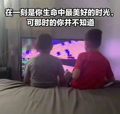 图片中两个儿童（分别穿着灰色和红色上衣）背对着镜头坐在床上，共同注视着前方电视屏幕上显示的像素风格游戏画面（疑似《我的世界》）。图片顶部有白色文字配黑色边框：“在一刻是你生命中最美好的时光，可那时的你并不知道”。整体场景营造出对童年简单快乐时光的怀念，以及长大后回望才意识到当时美好可贵的感慨。